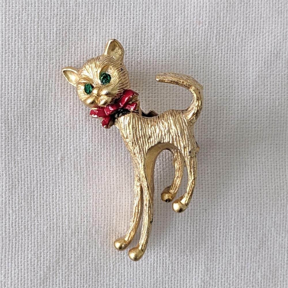1 1/4" Gold color Cat pin with Red Bow collar and green rhinestone eyes.